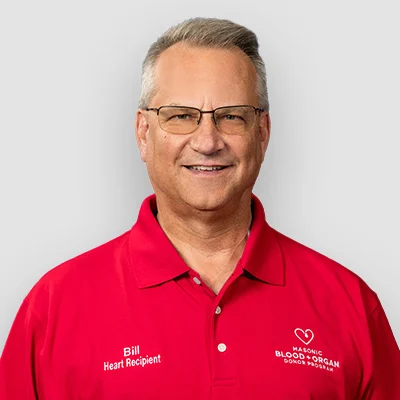 Smiling man with short hair and glasses wearing a red Masonic Blood & Organ Donors shirt