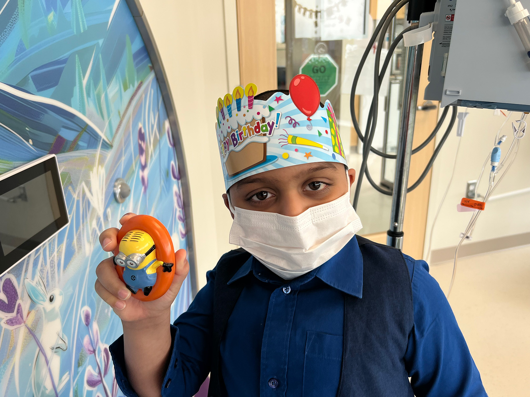 Photo-Jul-18-2025-2-20-06-PM Little boy in mask holding up minion toy