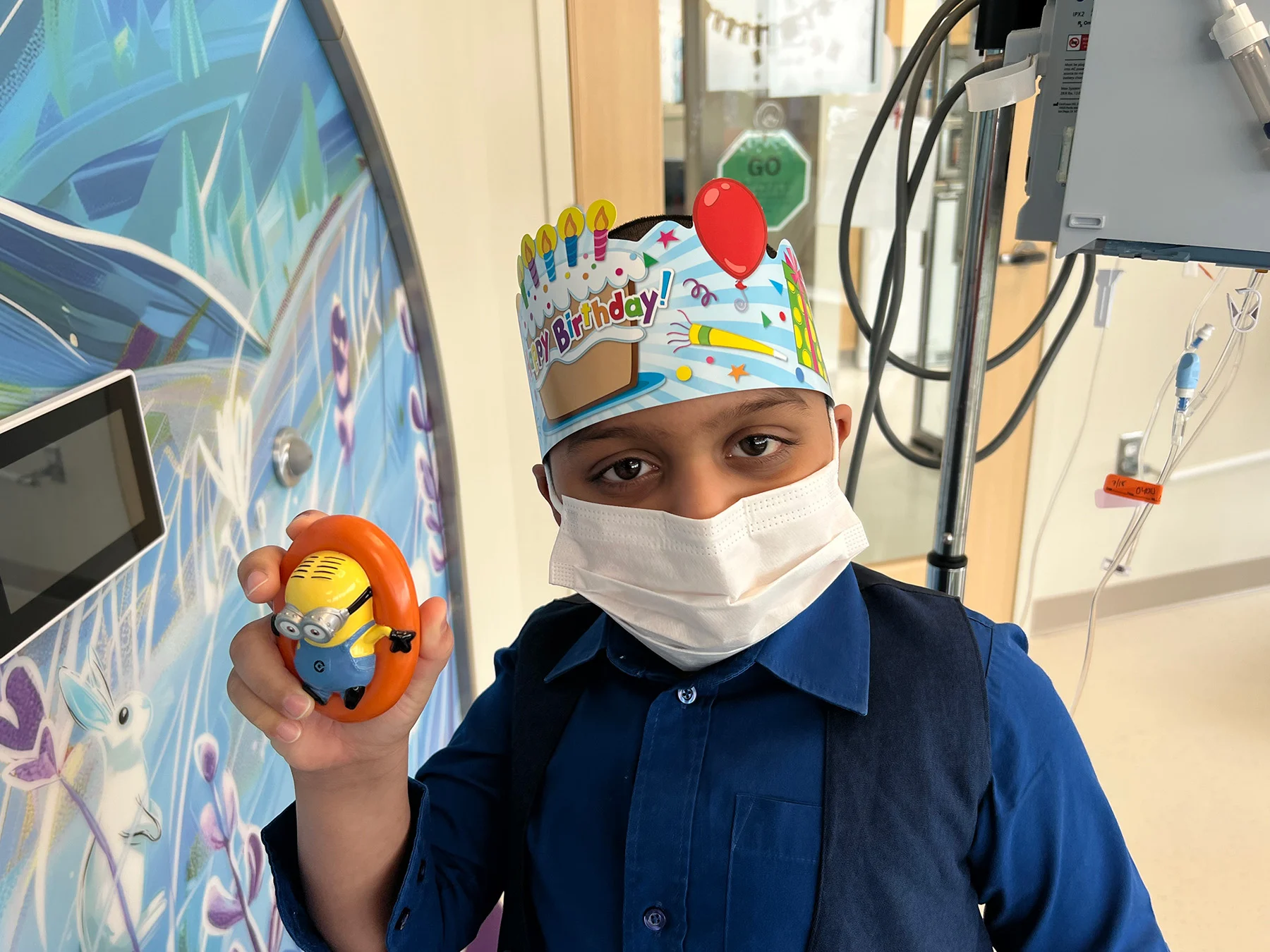 Photo-Jul-18-2025-2-20-06-PM Little boy in mask holding up minion toy